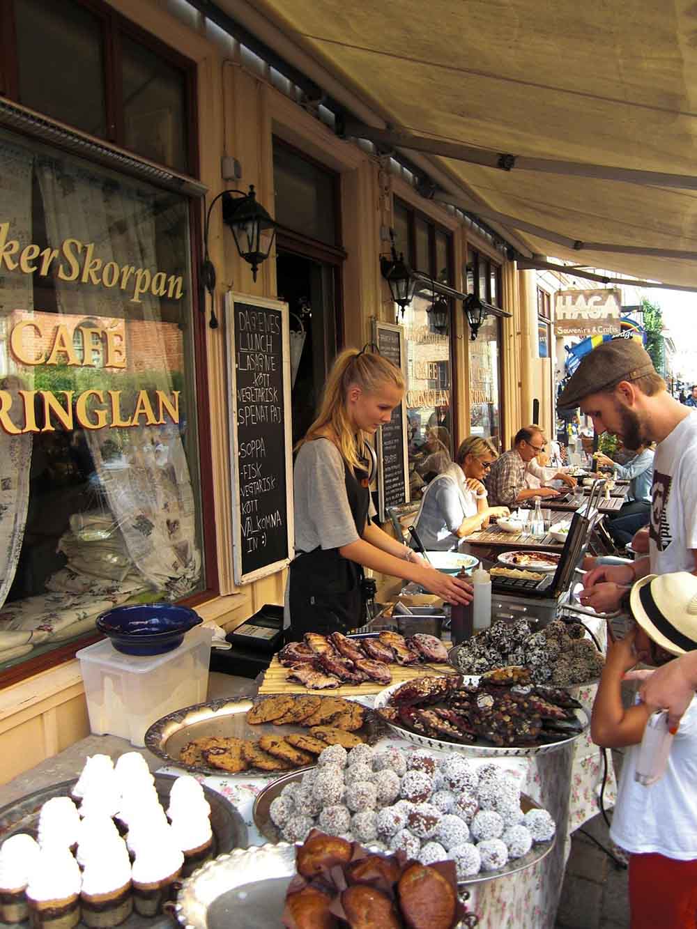 Cafetería callejera en Estocolmo con clientes consumiendo comida en un mercado urbano sueco
