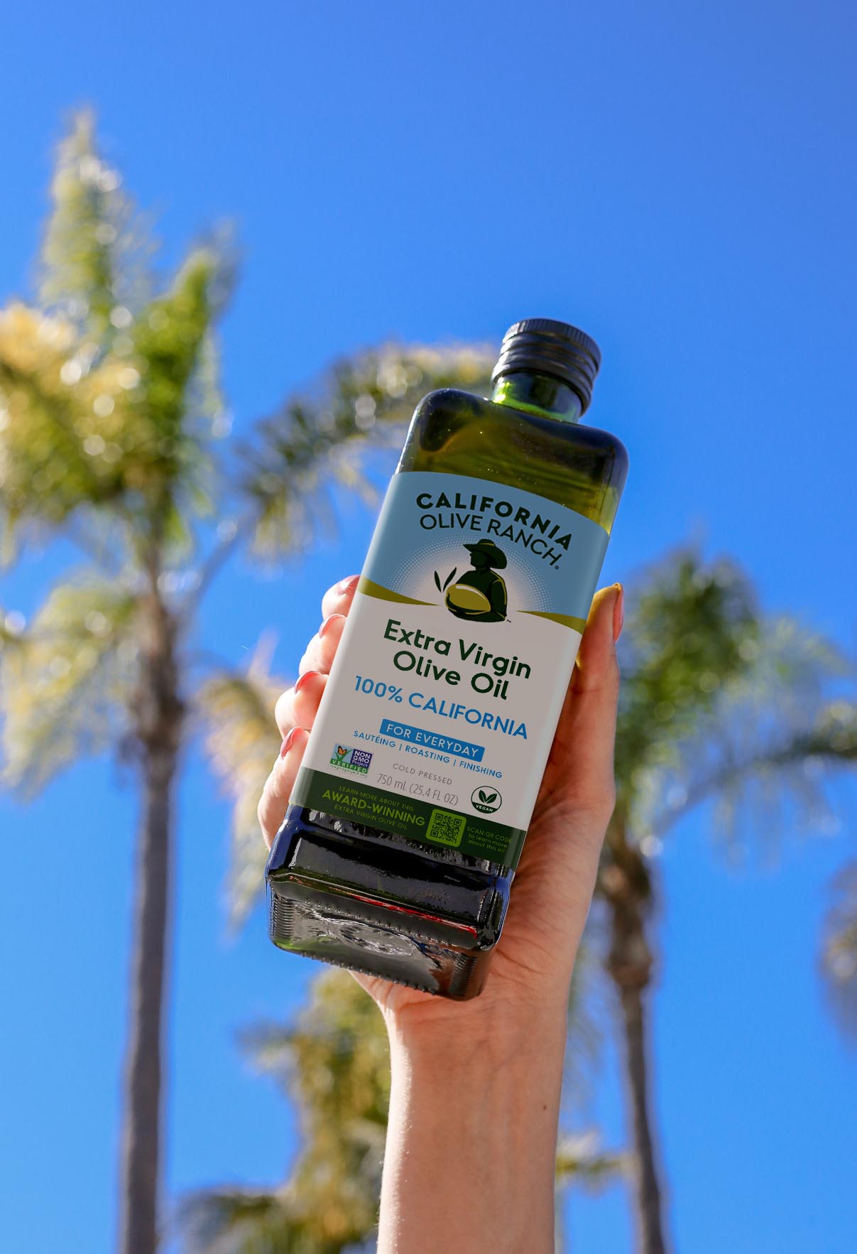 Botella de California Olive Ranch 100% California con palmeras al fondo
