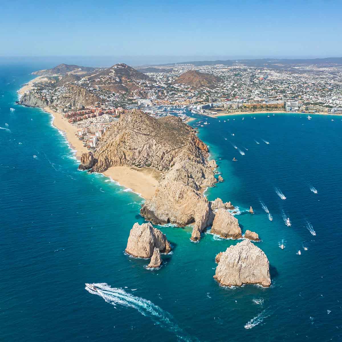 Vista aérea de Cabo San Lucas con hoteles, costa y embarcaciones turísticas